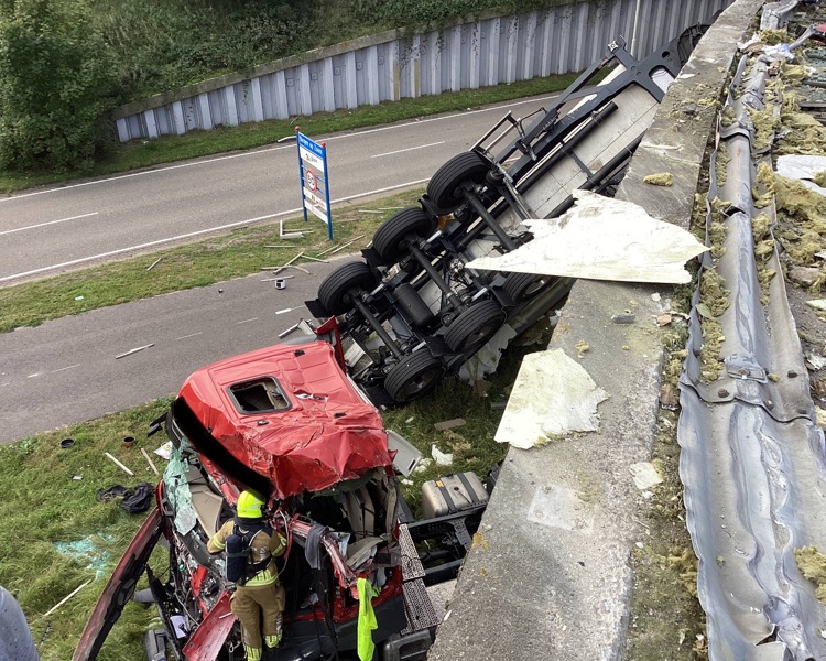 Vrachtwagen ligt op zijkant naast de weg naar beneden